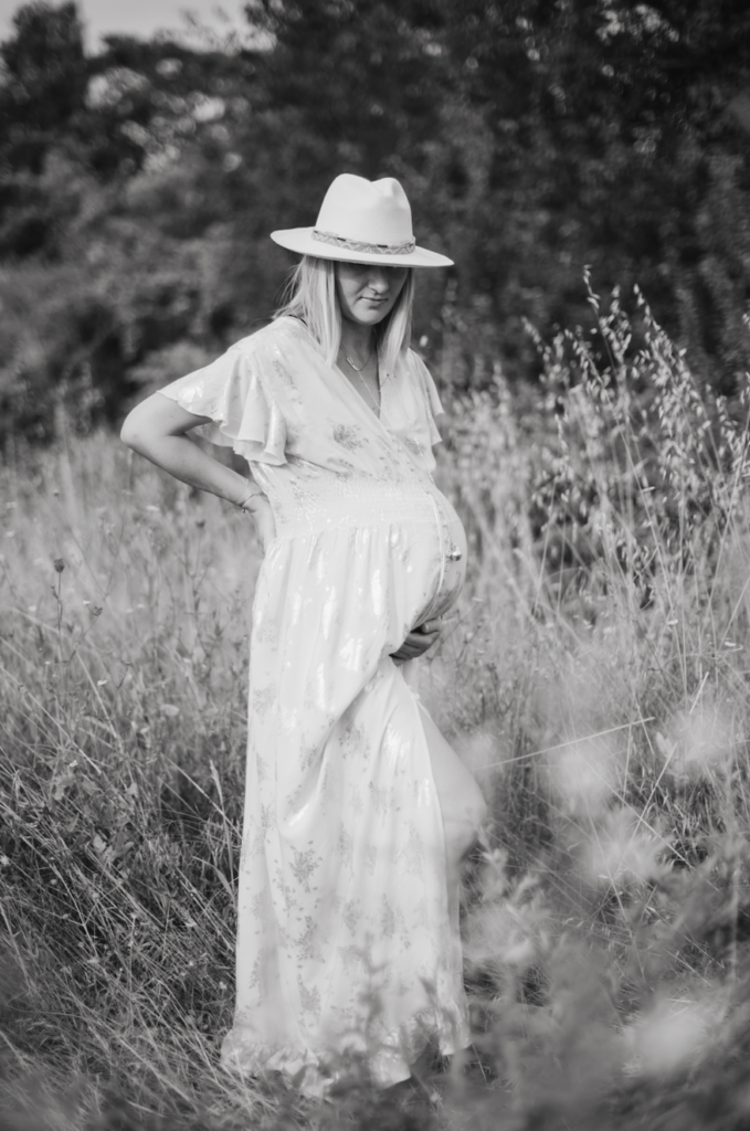 Photo de grossesse en extérieur dans les champs avec fleurs et robe d'été